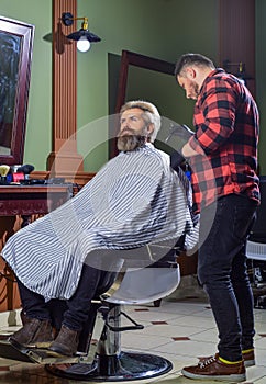 Loving his new style. beard and mustaches. Professional hairstylist in barbershop interior. Portrait of stylish man