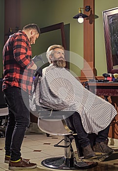 Loving his new style. beard and mustaches. Professional hairstylist in barbershop interior. Portrait of stylish man