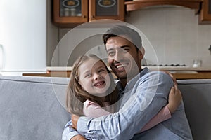 Loving Hispanic father cuddles his preschool daughter