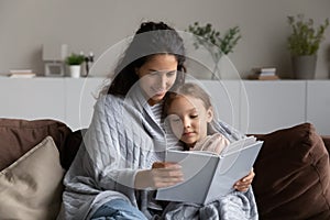 Loving Hispanic mom and daughter relax reading book