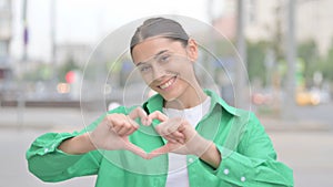 Loving Hispanic Woman showing Heart Shape by Hands Outdoor