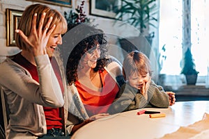 Loving homosexual women couple playing with their son while spending time together at home.