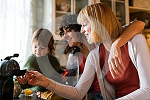 Loving homosexual women couple playing with their son while spending time together at home.