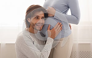 Loving husband listening to his pregnant wife`s belly