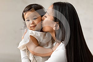 Loving Korean Mother Kissing Baby Daughter Expressing Love At Home