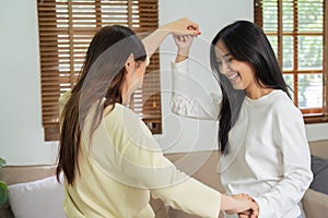 Loving LGBTQIA lesbian gay couple enjoy dancing together in the living room. Homosexual-LGBTQ concept.