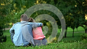 Loving male and female hugging sitting on grass in park, couple togetherness