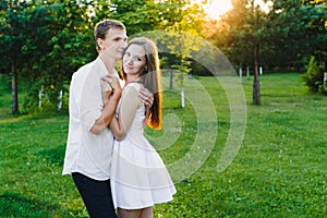 Loving man embraces his girl in a green area