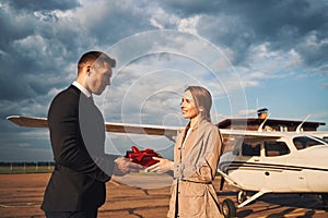 Loving man giving present to his girlfriend at airdrome