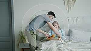 Loving man husband bringing breakfast on tray for happy wife in bedroom