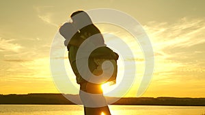 Loving man and woman dance in bright rays of sun on the background of the lake. Couple dancing at sunset on beach. Happy