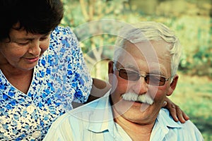 Loving mature cople hugs on a summer day in the park.Senior couple are sitting outdoors.An elderly woman hugs an old man