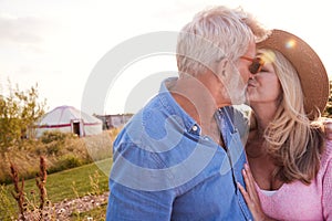 Loving Mature Couple In Countryside Kissing Against Flaring Sun