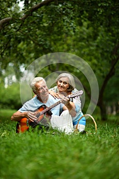 Loving mature couple with guitar in park