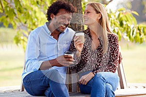 Loving Mature Couple Relaxing Sitting Together On Bench Under Tree In Summer Park With Coffee