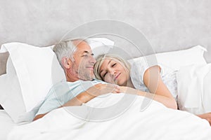 Loving mature man and woman lying in bed