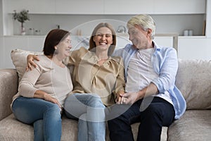 Loving mature parents and adult daughter woman sitting close