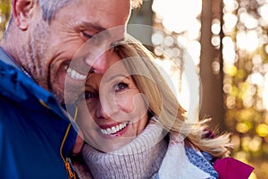 Loving Mature Retired Couple Hugging Against Autumn Countryside With Flaring Sun