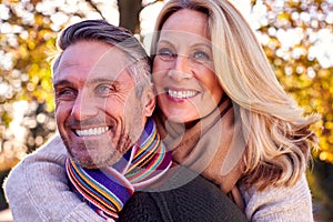 Loving Mature Woman Hugging Man From Behind As Retired Couple Walk Through Autumn Countryside