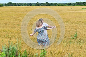 Loving middle-aged couple standing in field in summer