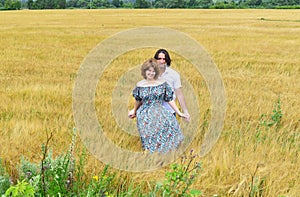 Loving middle-aged couple standing in field in summer