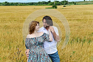 Loving middle-aged couple standing in field in summer