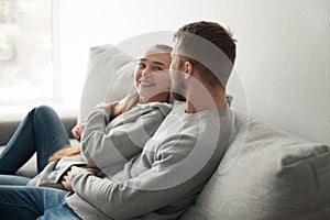 Loving millennial couple hugging relaxing on cozy couch