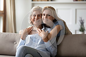 Loving millennial woman embracing from back senior mother in law