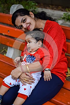 Loving mom carrying of her baby at society park. Bright portrait of happy mum holding child in her hands. Mother hugging her
