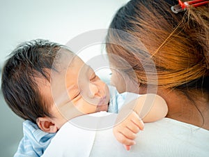 Loving mom carrying her sleeping newborn baby on her shoulder at home.Portrait of mum holding sleeping infant child on hands.
