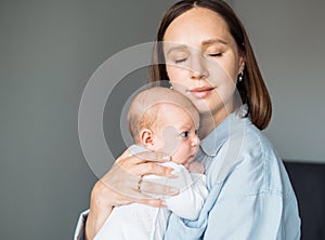 Loving mom carying of her newborn baby at home.