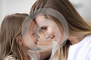 Loving mom and daughter look in eyes touching foreheads