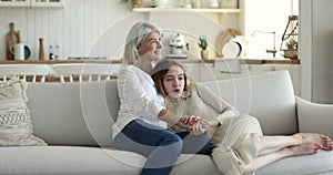 Loving mom hugging, talking to teenage daughter resting together indoors