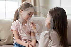 Loving mom talking to upset little child girl giving support