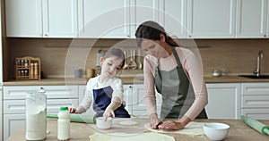Loving mom teach little daughter to prepare dough
