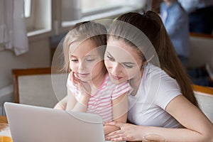 Loving mom watching cartoons with daughter at laptop