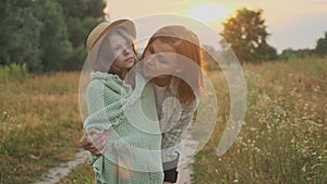 Loving moms puts on daughter knitted blanket, hugging child