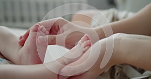 Loving mother arms gently hold adorable newborn baby's little feet close-up