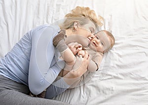 Loving mother caressing her baby boy on bed