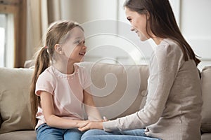 Loving mother and child holding hands talking sitting on sofa