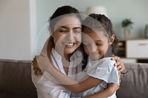 Loving mother cuddling daughter sit on sofa enjoy tender moment