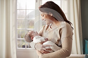 Loving Mother Cuddling Newborn Baby At Home