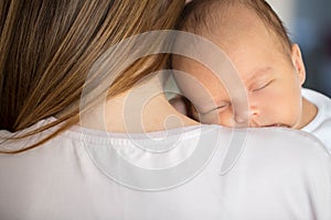 Loving Mother Cuddling Sleeping Newborn Baby Son Over Shoulder