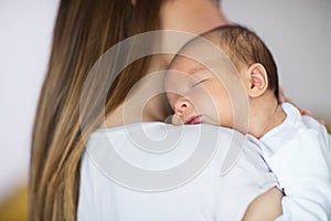 Loving Mother Cuddling Sleeping Newborn Baby Son Over Shoulder