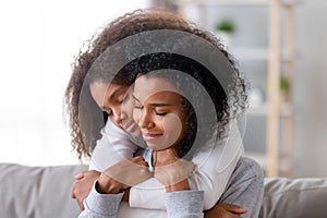 Loving mother and daughter with closed eyes embracing