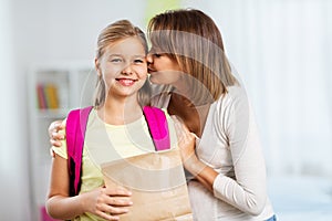 Loving mother giving daughter school lunch at home