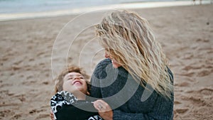 Loving mother having fun with cute little son on beach closeup. Happy child rest