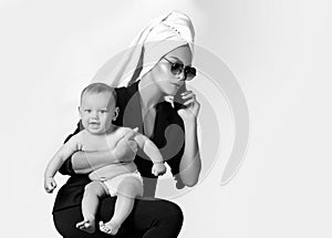 Loving mother with her baby. Young business woman speaking by phone and carrying her child with towel on head. Happy