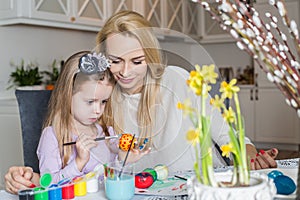 Loving mother and her daughter painting easter eggs