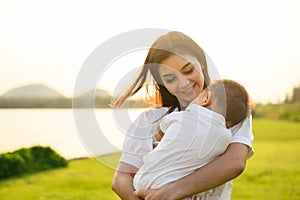 Loving mother holding and carrying her newborn baby at public park